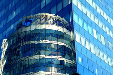 Glass house, high-rise office building, modern skyscraper in which round glass tower is reflected. Tall blue apartment building