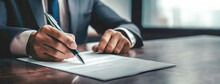 Professional Businessman Signing Contract Documents At Working Desk. A Close-up Of A Person's Hand Signing Papers, Conveying Focus And Business Acumen