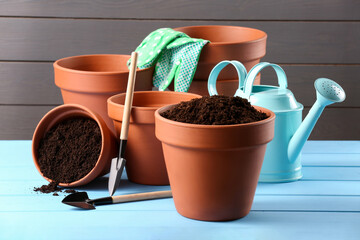 Wall Mural - Many terracotta flower pots with soil and gardening tools on light blue wooden table