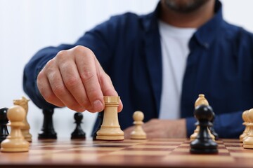 Wall Mural - Man with rook game piece playing chess at checkerboard, closeup