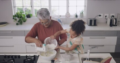 Canvas Print - Grandmother and child baking, cooking and making a cake, dessert and homemade cookies or biscuits in a home kitchen. Cute, fun and little girl helping senior with mixing pouring flour while bonding