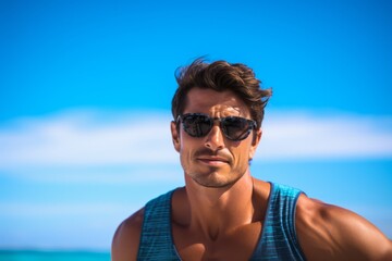 Wall Mural - Young handsome man in sunglasses and blue swimsuit on the beach.