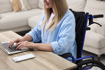 Canvas Print - Woman in wheelchair using laptop at home, closeup