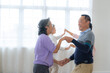 © ultramansk - Asian Older male and females people dance with their partners on a dancing floor in living space. Happy older couple performing get exercise. Joyful carefree retired senior friends enjoying relaxation