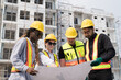 © amorn - Foreman builder male and female at construction site. Group of foreman construction working at construction site, wearing safety uniform, helmet and holding blueprint structure