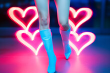 Glowing Neon Shaped Heart Lights With Slender Model Legs And Heeled Boots - Taking A Sexy Stance With Love This Valentine's Day - Retro Urban Street And Clubbing Culture Standout Fashion.