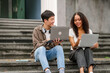 © M+Isolation+Photo - Group of young interracial diverse university students chatting together outside, engaging in a discussion together, college campus, enjoying campus recreation. Happy friends