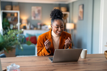 Smiling female business person feeling motivated while watching training webinar or having a video conference on laptop at home office.