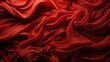 A vibrant maroon fabric cascades in rich folds, its peach undertones adding depth to the fiery red hue