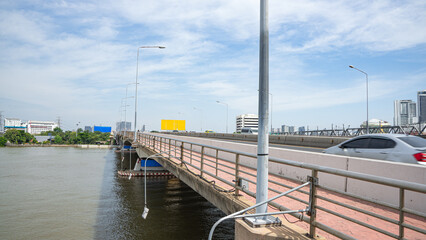 Picture of a bridge over a river with clear lane division There is a barrier between the dirt zone and the driving zone during the day. And there are lights from electric poles that shine brightly 