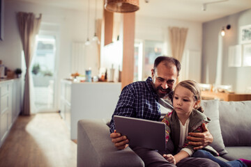 Father and daughter using tablet at home