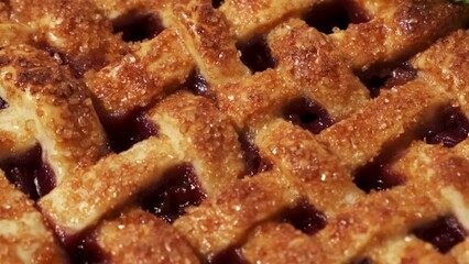 Sliding shot over delicious homemade cherry pie with Flaky Crust as a textured background. American traditional pastry. Flat lay. Fresh summer berry tart dessert sprinkled with sugar