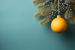 Gold bauble hanging on a Christmas tree branch on the right. Green background. Side view.Christmas banner with space for your own content.