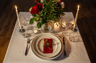 Wall Mural - holidays, romantic date and celebration concept - close up of festive table serving for two with flowers in vase and candles burning at home on valentine's day