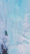 Ice Climbing on Frozen Waterfall, Aerial View. Mountaineer Man is Leading Ice. Barskoon Valley, Kyrgyzstan. Drone Flies Sideways. Vertical Video