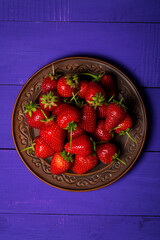 Red strawberry berries on a purple background, sweet strawberry