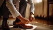 A man in a business suit ties the laces, groom tying shoes getting ready in the morning for the wedding ceremony.