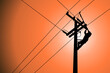Silhouette of power lineman closing a single phase transformer on energized high-voltage electric power lines.