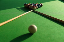 selective shot of billiard balls and cues on green snooker table