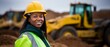 A joyful Afro-American female miner stands beside a massive haul truck, adorned in protective safety gear