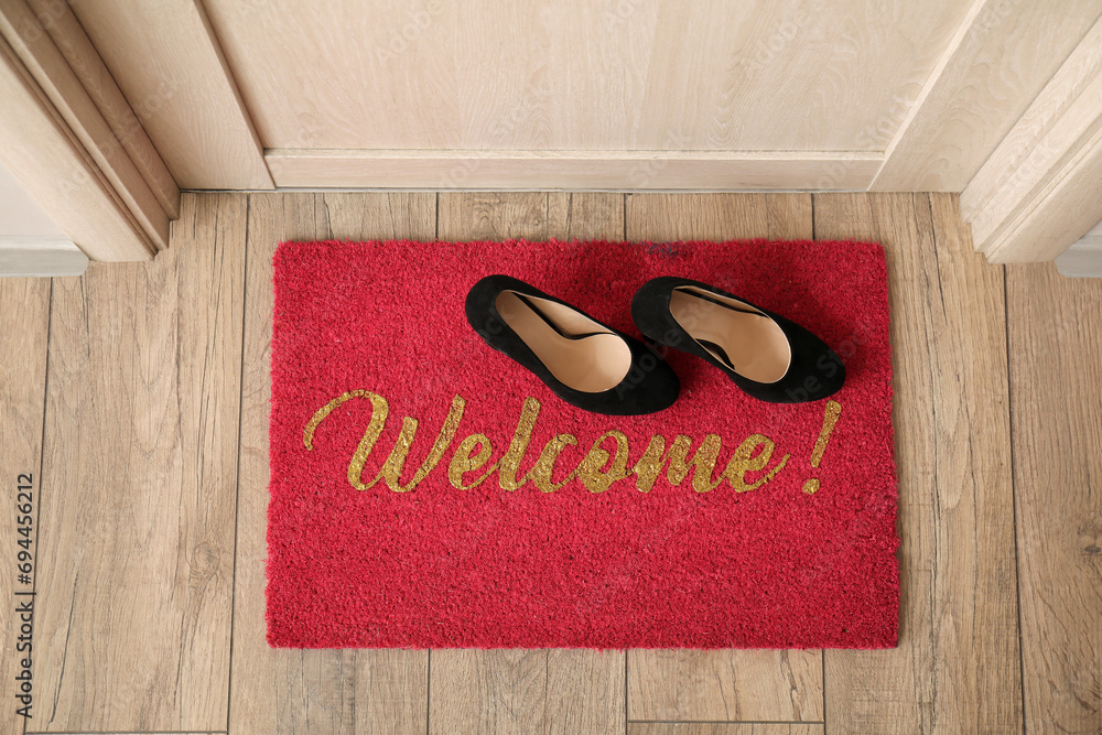 Welcome doormat with shoes in hall, top view