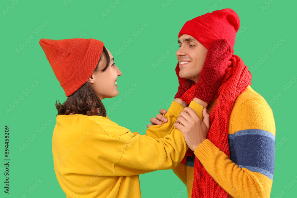 Happy young couple in warm clothes on green background