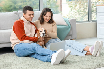 Poster - Young couple with cute Beagle dog and laptop at home