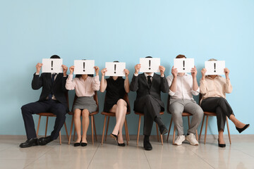 Canvas Print - Applicants holding paper sheets with exclamation marks near blue wall