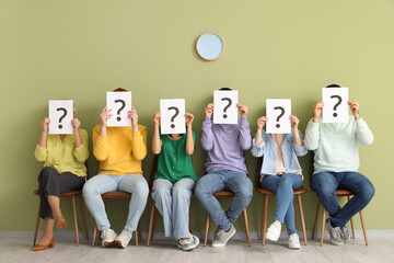 Wall Mural - Applicants holding paper sheets with question marks near green wall in room
