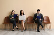 © Pixel-Shot - Young applicants waiting for job interview near beige wall