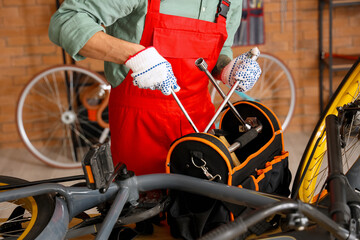 Sticker - Male mechanic repairing bicycle with cross wrench in workshop, closeup