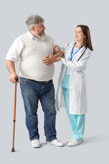 Poster - Mature man with walking stick and nurse on light background