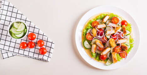 Poster - Tortilla with nuggets, vegetables and lettuce on a plate on the table top view web banner