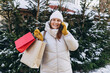 © mdyn - Happy young woman holding paper shopping bags talking on smart phone on winter street. In anticipation of the holidays, preparation and shopping concept. Redhead woman making phone call over mobile