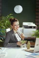 Wall Mural - happy modern woman employee in modern green office eating salad