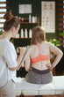 © Alliance - female therapist checking back condition during examination