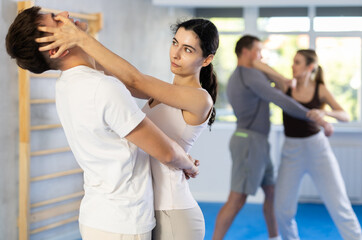 Aggressive young woman practicing self-defense techniques in pairs with guy during workout session