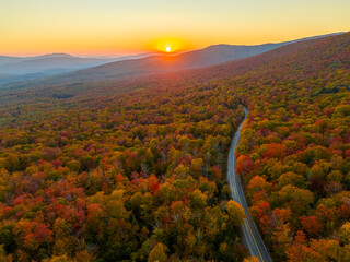 Wall Mural - aerial view of mountain road in colorful autumn forest during sunset