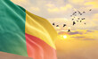 Waving flag of Benin against the background of a sunset or sunrise. Benin flag for Independence Day. The symbol of the state on wavy fabric.