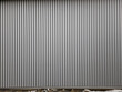 © Michal - building is lined with square panels. metal sheet wall cladding with scalloped design. corrugated sheet, dark gray, riveted. horizontal stripes, shadows, corner, fence, aluminium, sheet