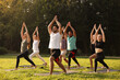 © New Africa - Group of people practicing yoga on mats outdoors