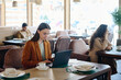 © Westend61 - Young businesswoman sitting with coffee cup and working on laptop at restaurant