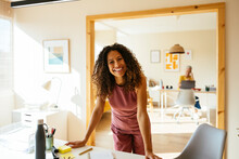 Smiling businesswoman with curly hair standing at desk in office