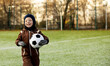 © Westend61 - Smiling boy with ball standing at soccer field