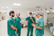 © Westend61 - Surgeon using smart phone having discussion with colleagues in hospital