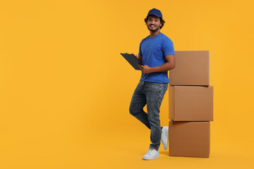 Wall Mural - Happy courier with clipboard and stack of parcels on orange background, space for text