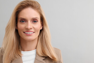 Canvas Print - Portrait of smiling middle aged businesswoman on light grey background. Space for text