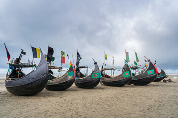 Poster - Scenic landscape view of row of traditional wooden fishing boats known as moon boats on beach under moody sky, Cox's Bazar, Bangladesh