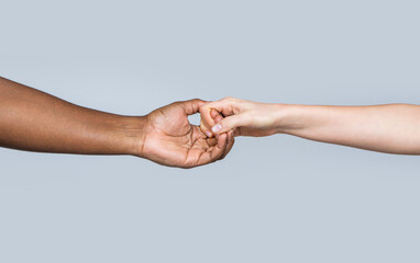 Wall Mural - White Caucasian female hands and black african american holding fingers together. Woman and african woman hand. Helping hand, rescue. Helping hands, rescue gesture. Black and white human hands