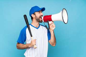 Wall Mural - Young man playing baseball over isolated blue background shouting through a megaphone